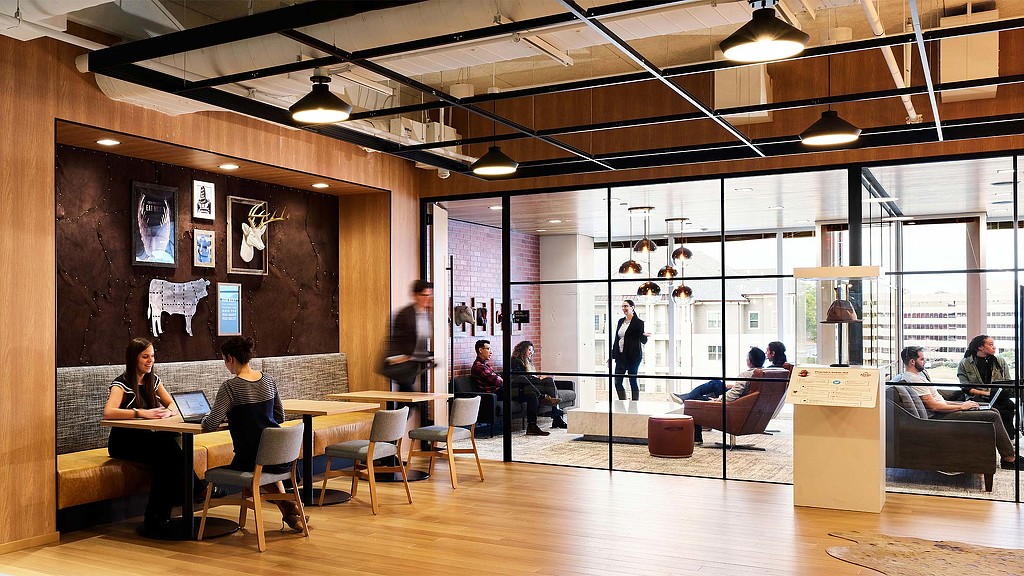 A group of people sitting in a room with a wood floor.
